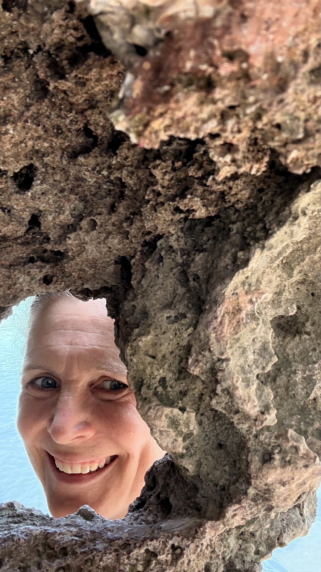 Christina lacht durch ein Fenster im Felsen