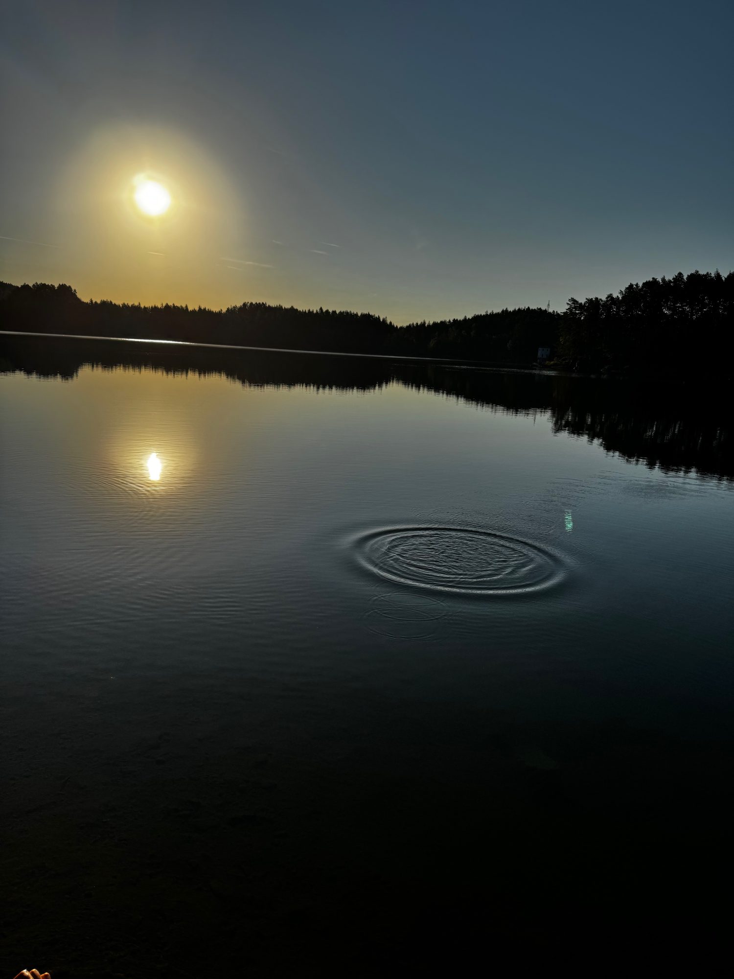 Abendlicht über einem stillen See, Ringe auf dem Wasser