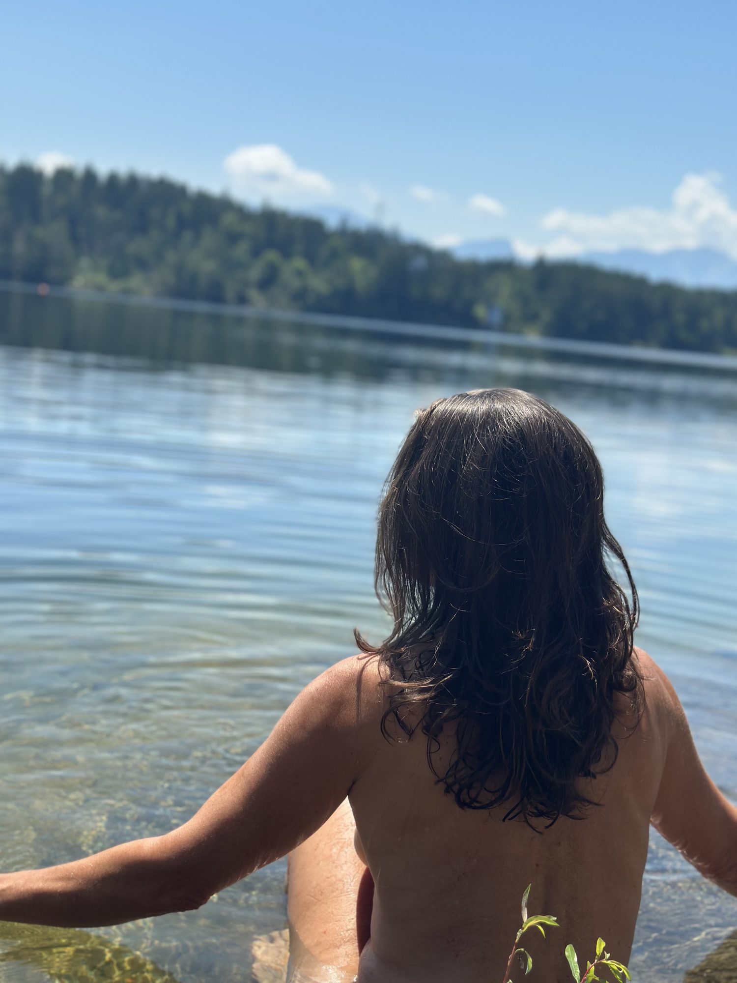 Christina von hinten, sie steigt in einen See, das Haar über dem Rücken